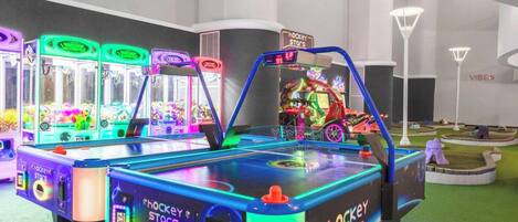 Un salón de juegos interior con varias máquinas de pinza y una zona temática de hockey.