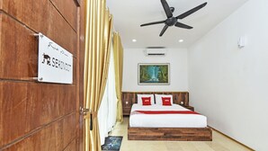 Une chambre d’hôtel avec un lit, un ventilateur de plafond, un tableau au mur et une pancarte sur la porte.