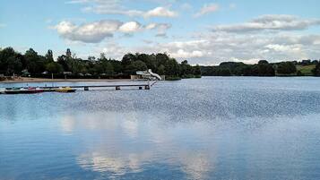 A calm lake with a dock and boats, surrounded by trees and a clear sky.
