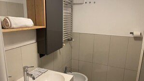 A bathroom with a sink, mirror, towel rack, toilet, and a towel on the rack.