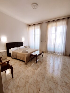 Relax in a spacious room with a large bed, bedside tables, and a marble floor.