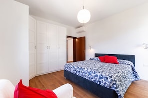 A bedroom with a bed, a wardrobe, a door, and a ceiling light.