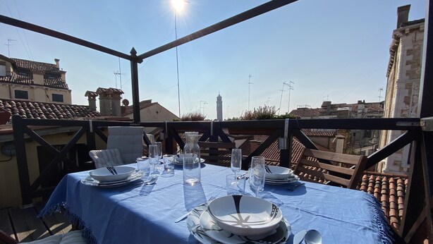 A table set for two with a blue tablecloth, white plates, silverware, and clear glasses. - Apartment, A stone's throw from St. Mark's with a lovely view  (Venezia)