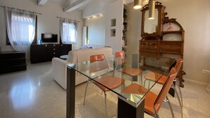 A modern living room with a glass dining table, sofas, a TV, and a wooden cabinet. - Apartment, A stone's throw from St. Mark's with a lovely view  (Venezia)