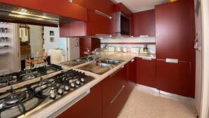 A modern kitchen with red cabinets, stainless steel appliances, and a central island with a sink. - Apartment, A stone's throw from St. Mark's with a lovely view  (Venezia)
