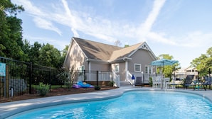 A swimming pool with a house in the background, surrounded by a fence and trees. - Single level, Interior home with Private Pool and Golf Cart in Spinnaker's Reach (Emerald Isle)