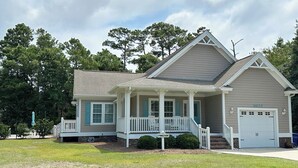A two-story house with a front porch, a garage, and a well-maintained lawn. - Single level, Interior home with Private Pool and Golf Cart in Spinnaker's Reach (Emerald Isle)