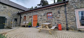 Enjoy outdoor dining and relaxation at this charming stone building with a picnic table and outdoor cooking facilities.