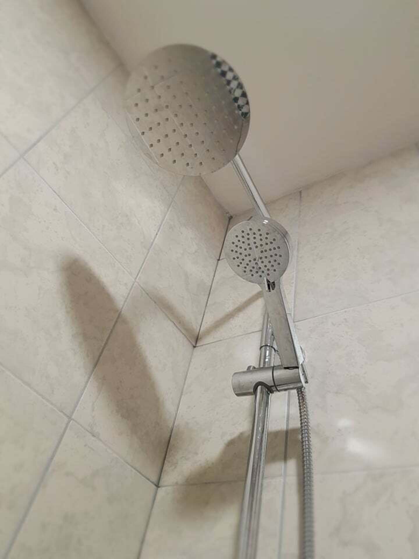 A shower with a handheld showerhead and a fixed showerhead.