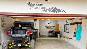 A garage with a mountain-themed wall, a black ATV, and a wooden bench. - Mountain Memories, Walk to Ski Area, Town, Fishing (Red River)