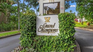 Une enseigne indiquant « Grand Champions », avec le chiffre 155 au-dessus, le tout entouré d’une végétation luxuriante.