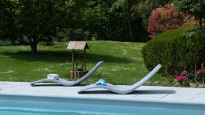 A swimming pool with two lounge chairs and a wooden structure in the background. - VILLA FOUILLEBROC with swimming pool (Touffreville)