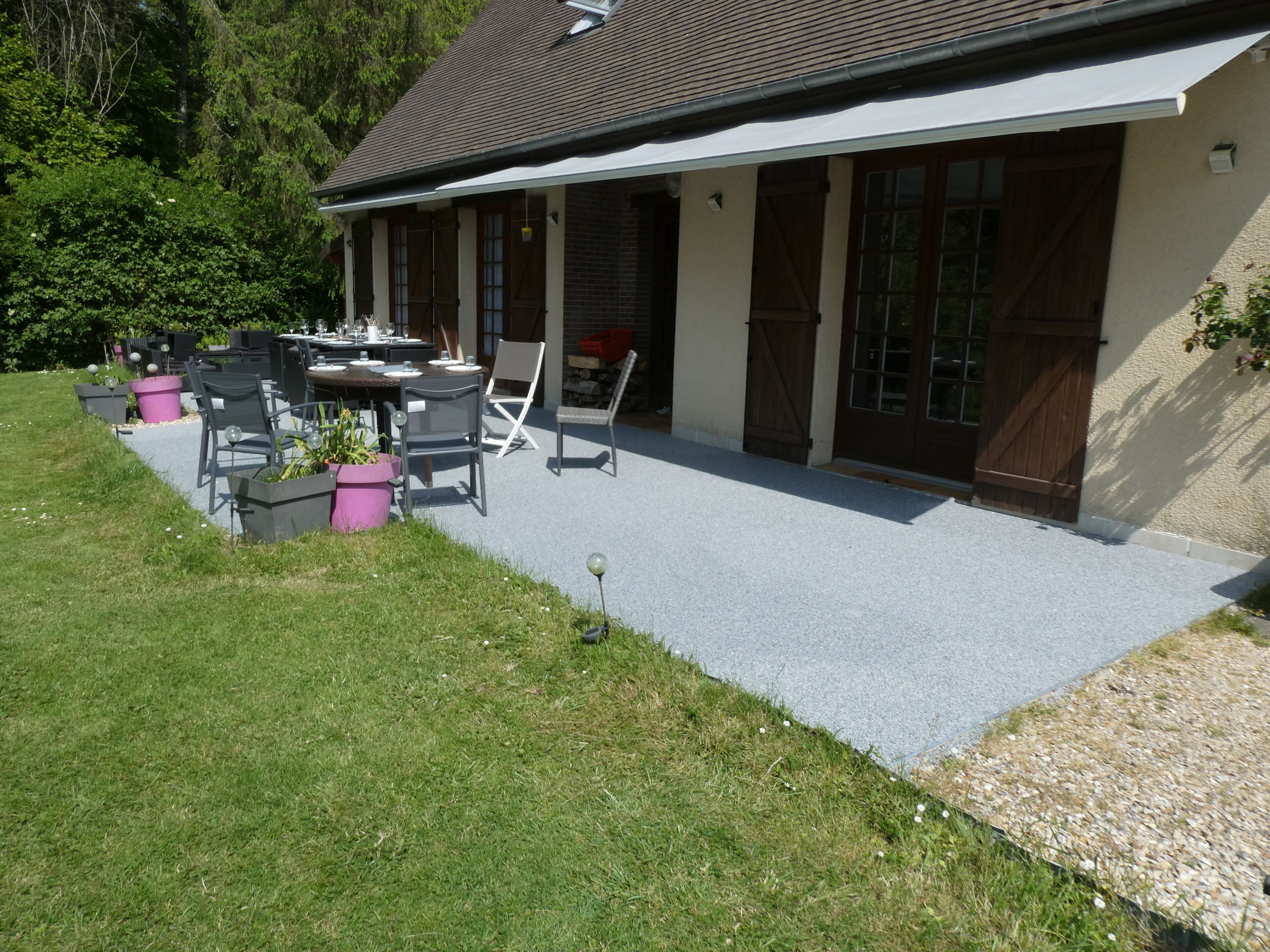 Ein Haus mit überdachter Terrasse, Gartenmöbeln und einem Garten.