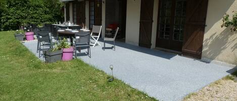 A house with a covered patio, outdoor furniture, and a garden.
