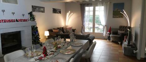 A dining area with a table set for a meal, a fireplace, and a Christmas tree.