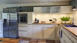 A modern kitchen with a stainless steel refrigerator, built-in oven, and a wooden countertop.
