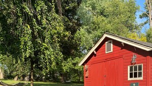 Un edificio de madera roja con un sendero de piedra que conduce a él, rodeado de follaje y árboles.