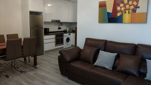 A modern living room with a brown leather sofa and a dining area with a table and chairs.