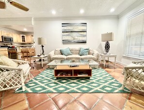 Un salon avec un canapé, une table basse et un tapis à motifs.