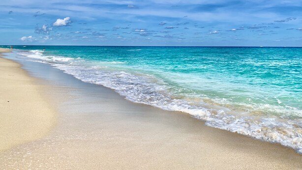 Una spiaggia con acque cristalline turchesi e una riva sabbiosa.