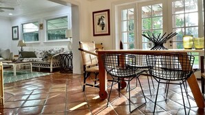 Zona pranzo con tavolo in legno, sedie in filo nero e lampadario.