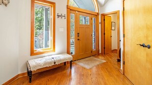 A hallway with wooden flooring, a bench, and a large arched window. - Game Room, Sauna, Bonus Apartment Near Wintergreen Resort! (Nellysford)