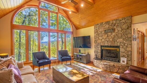 A cozy living room with a stone fireplace, large windows, and comfortable seating. - Game Room, Sauna, Bonus Apartment Near Wintergreen Resort! (Nellysford)