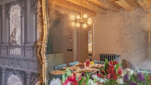 Ein Essbereich mit Holzbalkendecke, einer Kronleuchter und einem Tisch für zwei Personen, gedeckt mit Blumen und einer Obstschale.