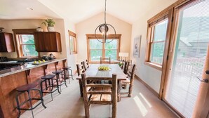 Une cuisine spacieuse dotée d’un grand îlot central, de tabourets de bar et d’une table à manger avec des chaises en bois.