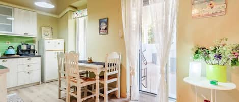 A kitchen with a dining table and chairs, a refrigerator, and a window with curtains.