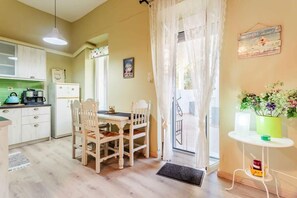 Una cucina con tavolo e sedie, un frigorifero e una finestra con tende.