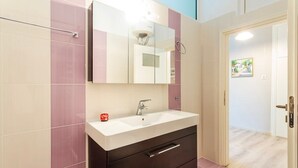 A bathroom with a white sink, dark cabinet, and a mirror above it.