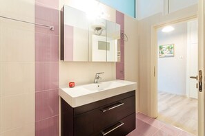 A bathroom with a white sink, dark cabinet, and a mirror above it.