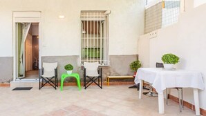 A patio area with a table, chairs, and potted plants.