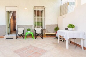 A patio area with a table, chairs, and potted plants.