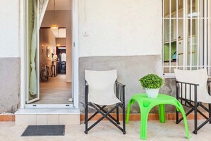 A small outdoor seating area with a chair, a table, and a potted plant.
