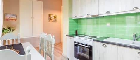 A kitchen with white cabinets, a green backsplash, and a stove.