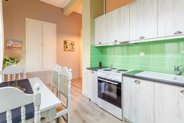 A kitchen with white cabinets, a green backsplash, and a stove.