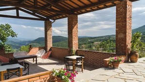 An outdoor patio with brick columns, a table, chairs, and potted plants. - Le Fonti - Monteloro, large and bright (Pontassieve)