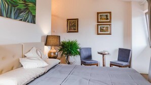 A hotel room with a bed, two chairs, a small table, a lamp, and framed pictures on the wall. - Le Fonti - Monteloro, large and bright (Pontassieve)