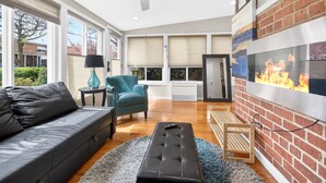 Een moderne woonkamer met een bank, een blauwgroene fauteuil, een salontafel en een open haard.