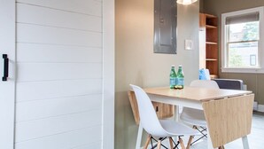 Un comedor con una mesa de madera, sillas blancas y un ventilador de techo.