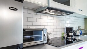 Una cocina moderna con un refrigerador de acero inoxidable, un horno tostador empotrado y una cafetera sobre la encimera.