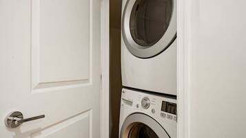 A white door with a silver handle, leading to a laundry room with two stacked washing machines.