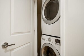 A white door with a silver handle, leading to a laundry room with two stacked washing machines. - Two Suites - Private Baths - Walk to Union Station (Washington)