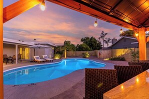 Ein Schwimmbecken mit Liegestühlen und einer überdachten Terrassenanlage.