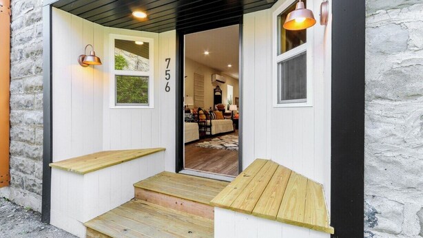 Un escalier en bois mène à une porte blanche portant le numéro 756.