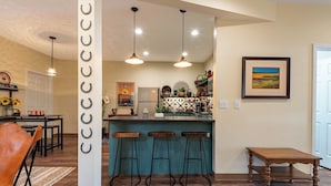 Une cuisine moderne dotée d’un îlot de couleur turquoise, d’un éclairage suspendu et d’un coin bar avec des tabourets.