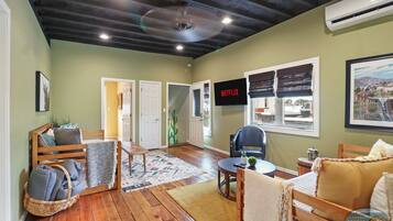 A cozy living room with a wooden bench, a small table, and a TV displaying 'NETFLIX'.