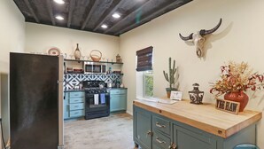 A kitchen with a black refrigerator, a wooden countertop, a cactus, and a wall-mounted cow skull. - Downtown Lake Geneva Hideaway Balcony Walk to Beach Live Music Sleeps 8 (Lake Geneva)